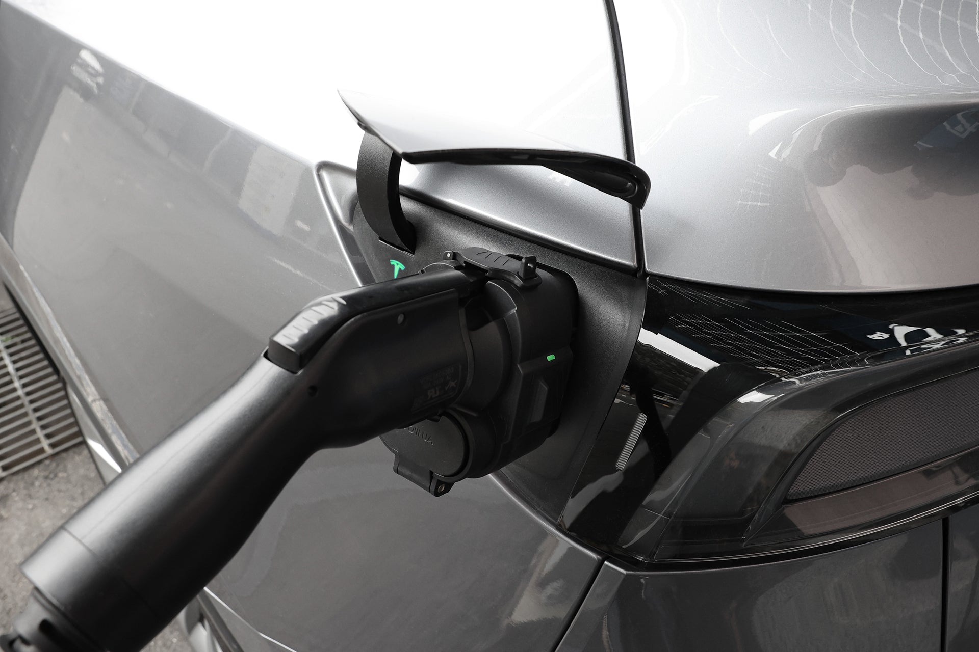 A close-up of a silver electric vehicle charging with a JOWUA CCS1 to CCS2 DC & AC Combined Adapter and black cable connected to the car’s port.