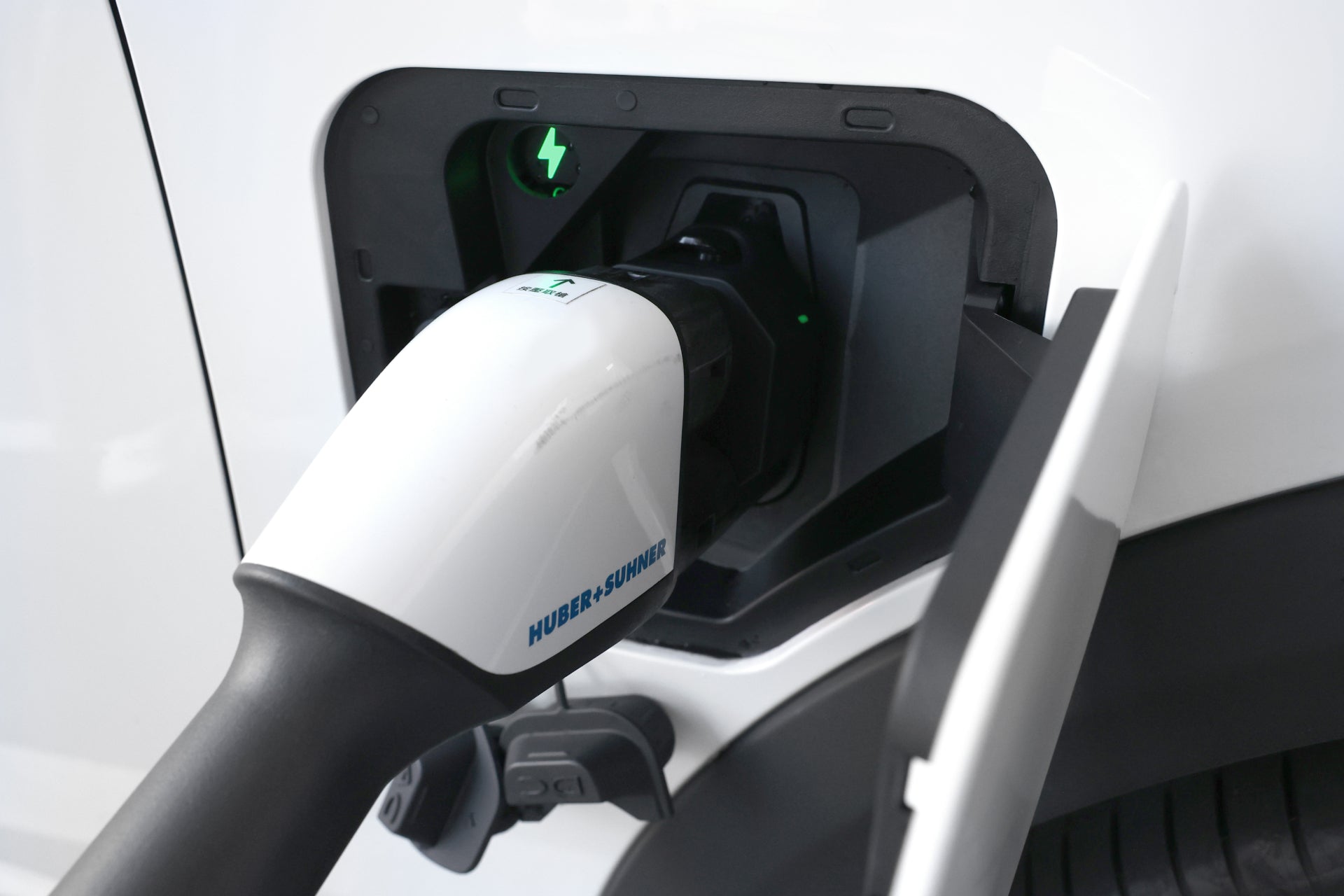 A gleaming pure white electric car is charging via a JOWUA CCS2 to CCS1 DC & AC Combined Adapter. It
