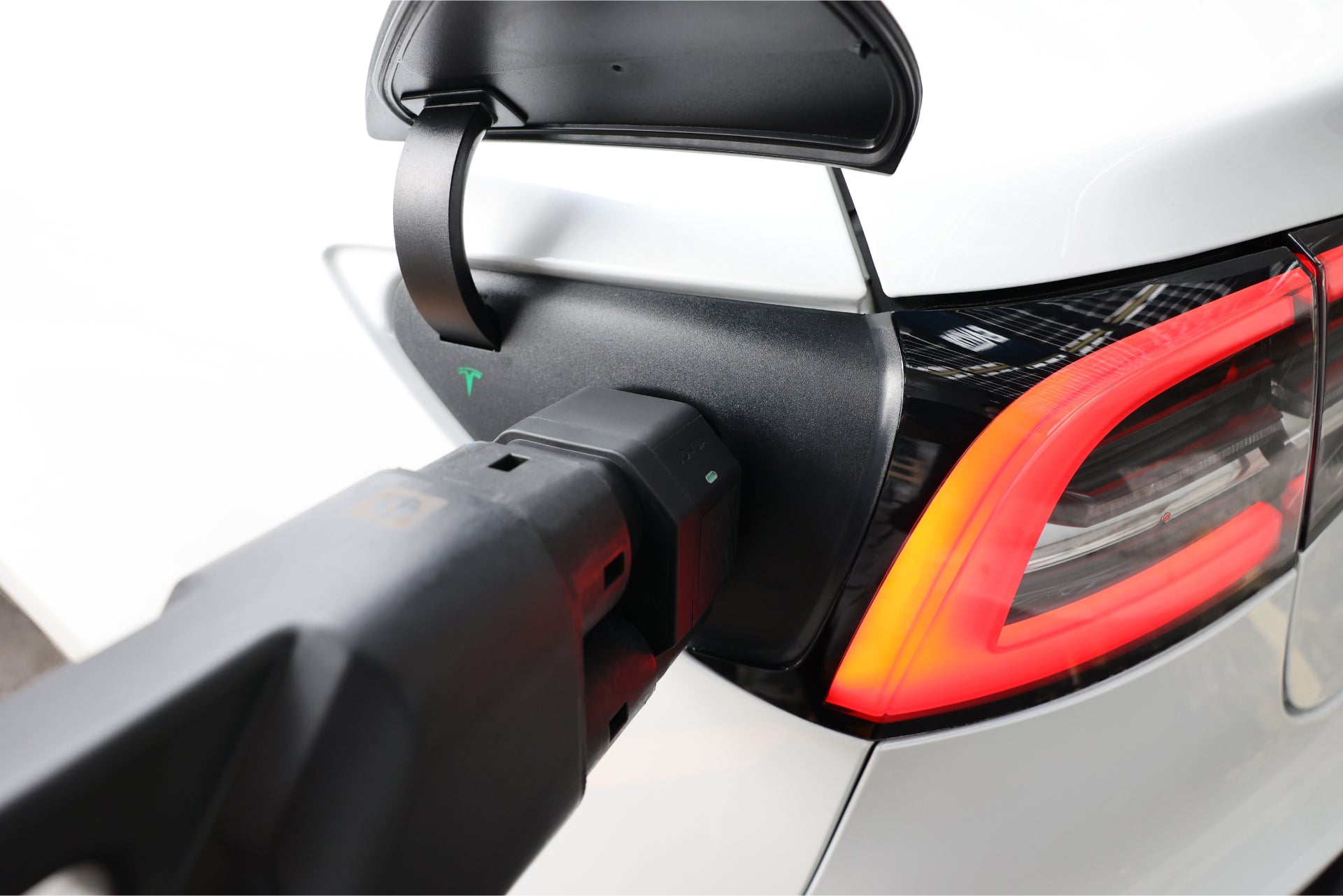 A white electric car is being charged with a JOWUA CCS2 to NACS DC Charging Adapter. The vehicle