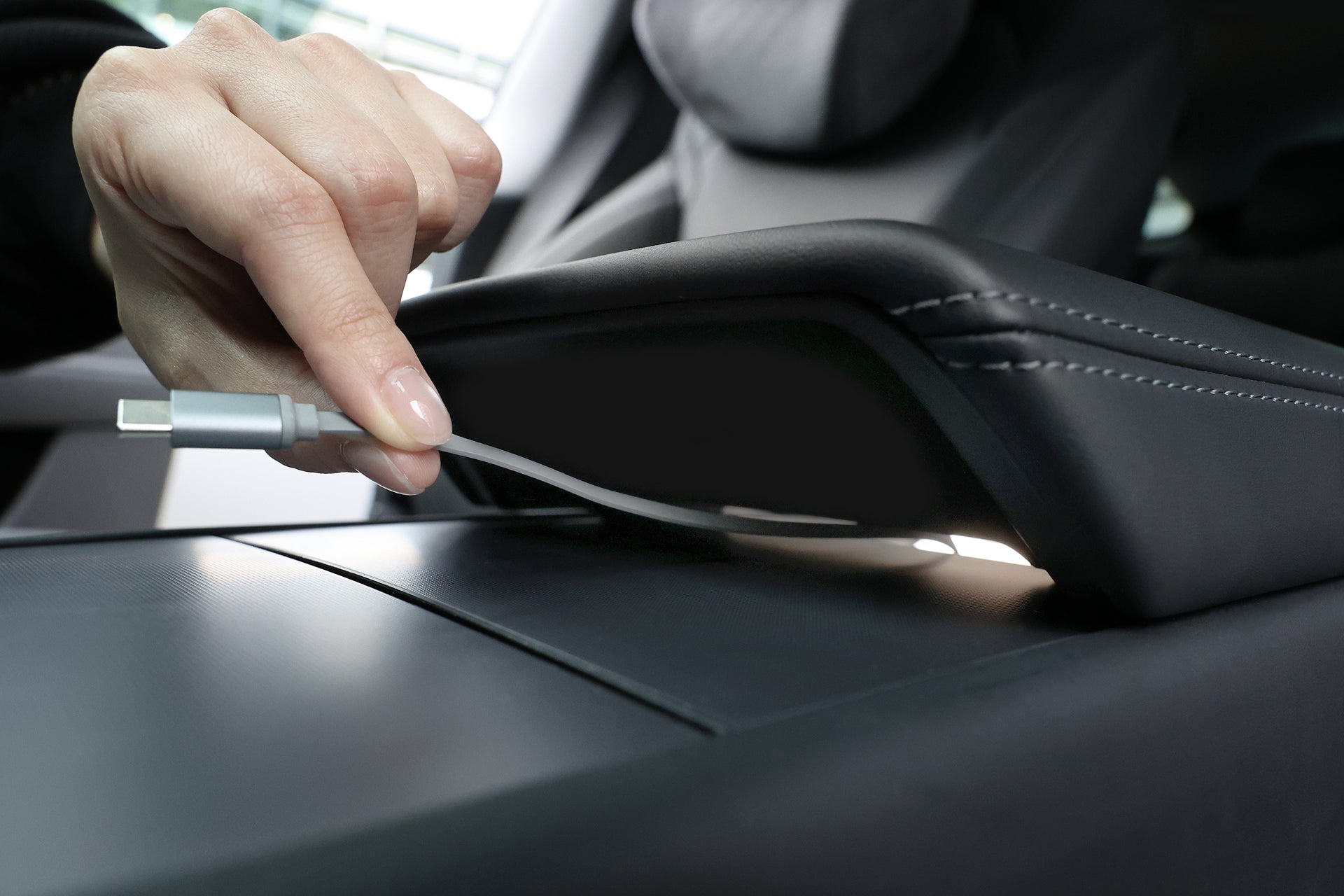 A hand lifts a Model 3 armrest, revealing the JOWUA Center Console Organizer Set with Power HUB (2024-2026+) for neat storage and easy device charging.