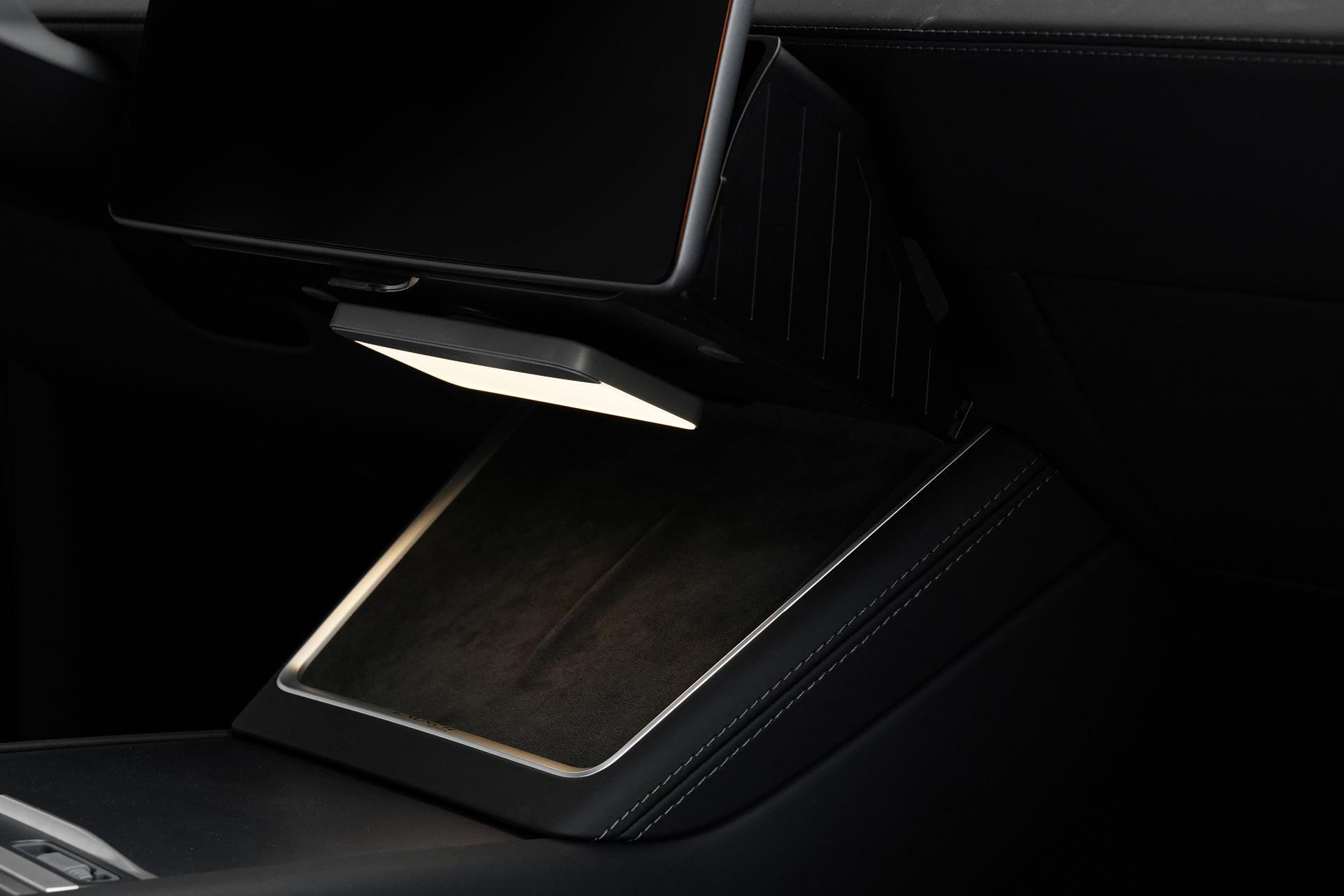 A close-up of a car’s modern dashboard showcases the JOWUA Under Screen Invisible Station, seamlessly integrated beneath a large touchscreen with dark, sleek materials, visible stitching, and clever concealed storage in the center console.