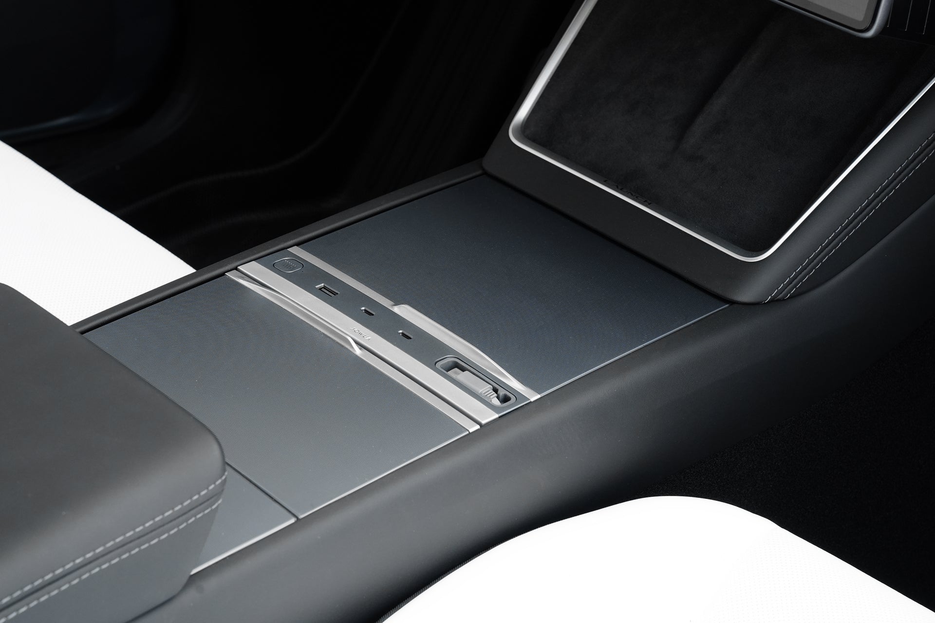 Close-up of a modern car’s center console with a sleek black and silver design and white leather seats—ideal for displaying JOWUA’s 130W LED Hub for Tesla Model Y Juniper 2025+ / Model 3 2024+.