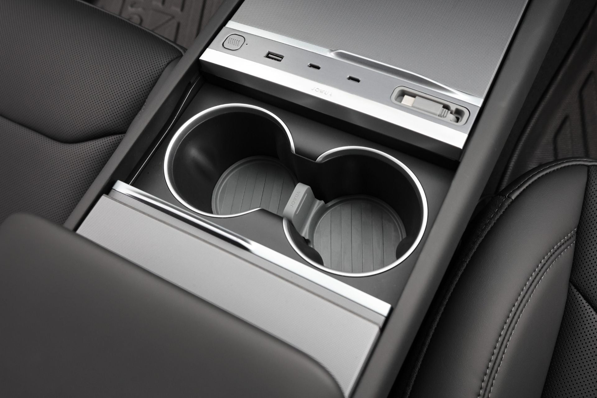 A close-up of the JOWUA Center Console Set for Tesla Model Y Juniper 2025+ shows two cup holders with silicone mat, USB port, button, storage compartment, and stylish black and silver design—ideal for center console organizer upgrades.