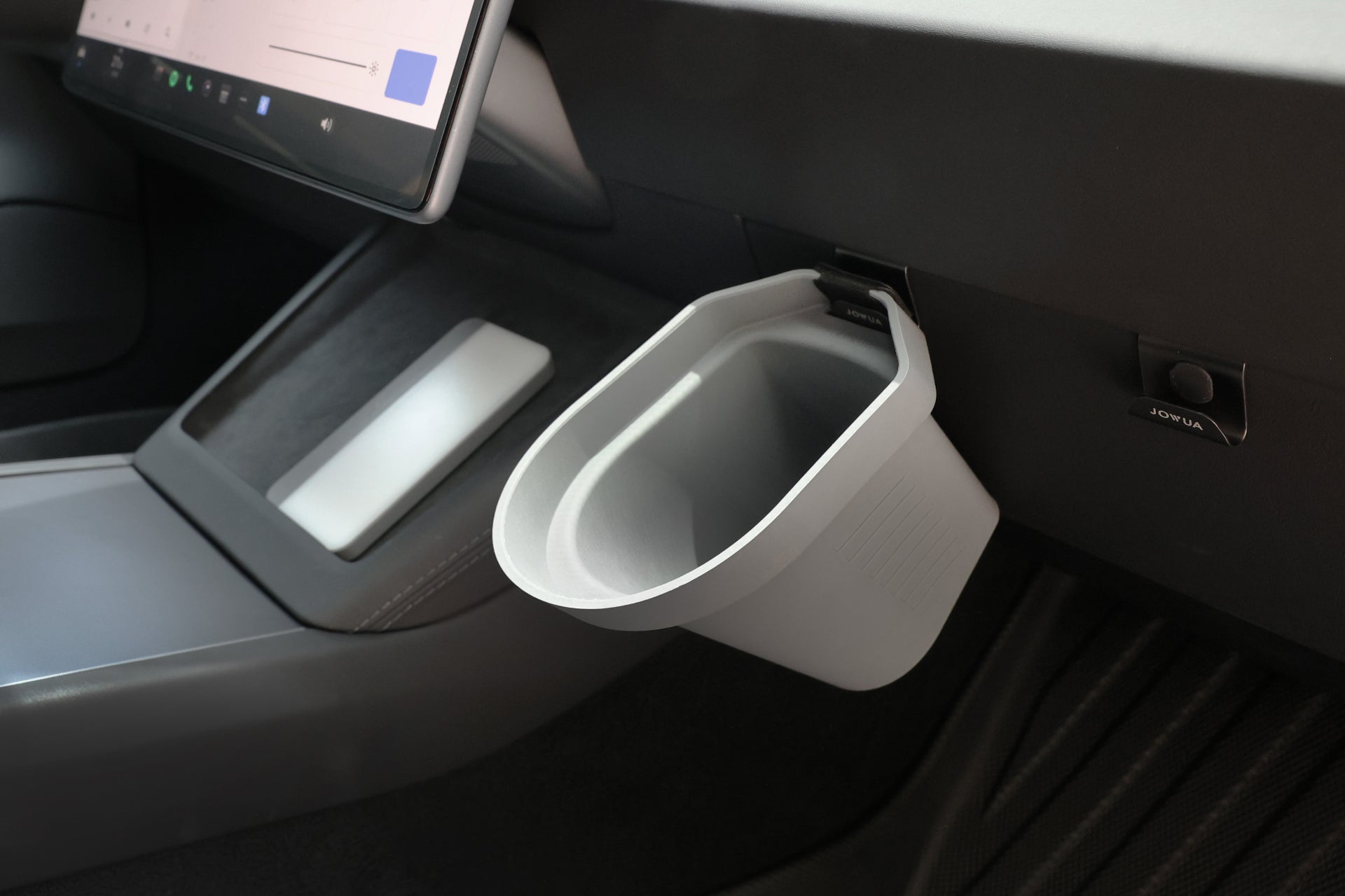 A JOWUA Door Side Storage Box, finished in gray silicone, is affixed to the passenger side dashboard of a Tesla Model, adjacent to the touchscreen display. The rectangular storage box, with its wide opening, perfectly complements the sleek and modern design of the vehicle's interior.