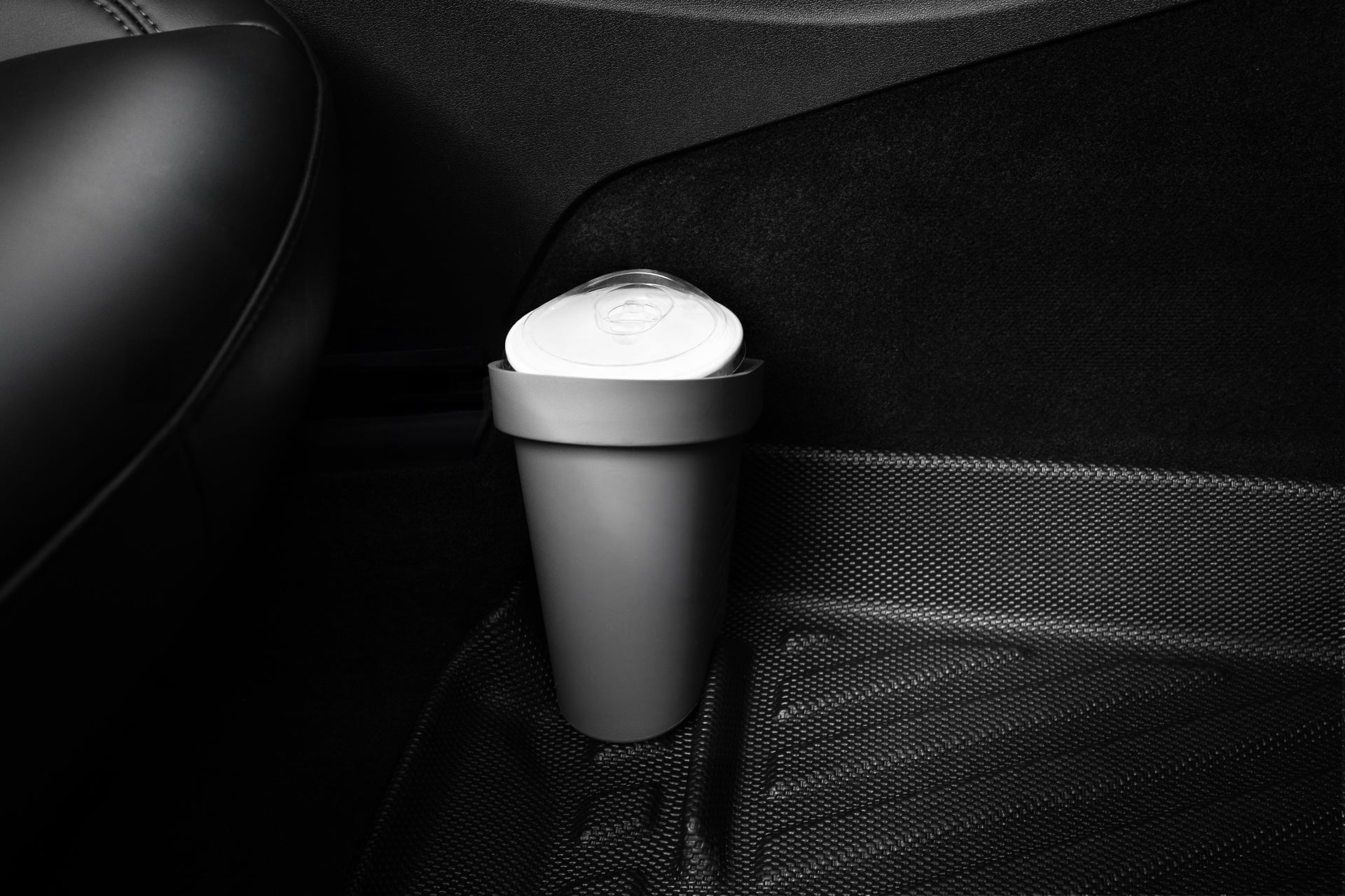 A JOWUA Door Side Storage Box from a set of two holds a cup with a lid in the storage compartment on the door panel of a Tesla Model S. The car's interior boasts a sleek and modern appearance, highlighted by a dark color scheme and luxurious silicone materials, while the floor is adorned with a textured mat.
