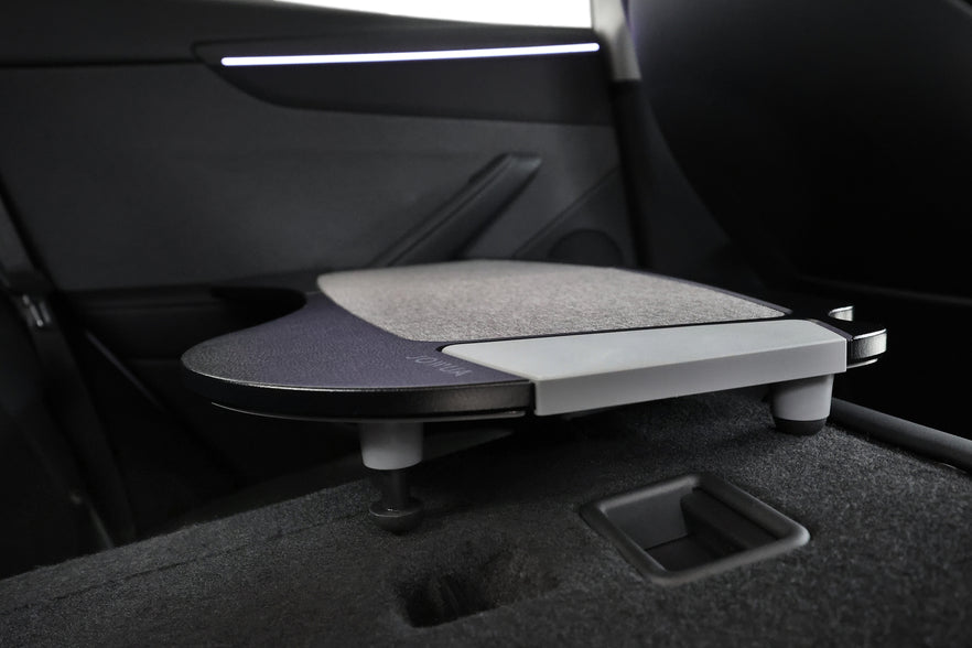 A close-up of the JOWUA Foldable Car Tray for Tesla extended in the rear seat, showing its textured surface and modern design, with the car’s interior door and seat in view—an innovative accessory for Tesla vehicles.