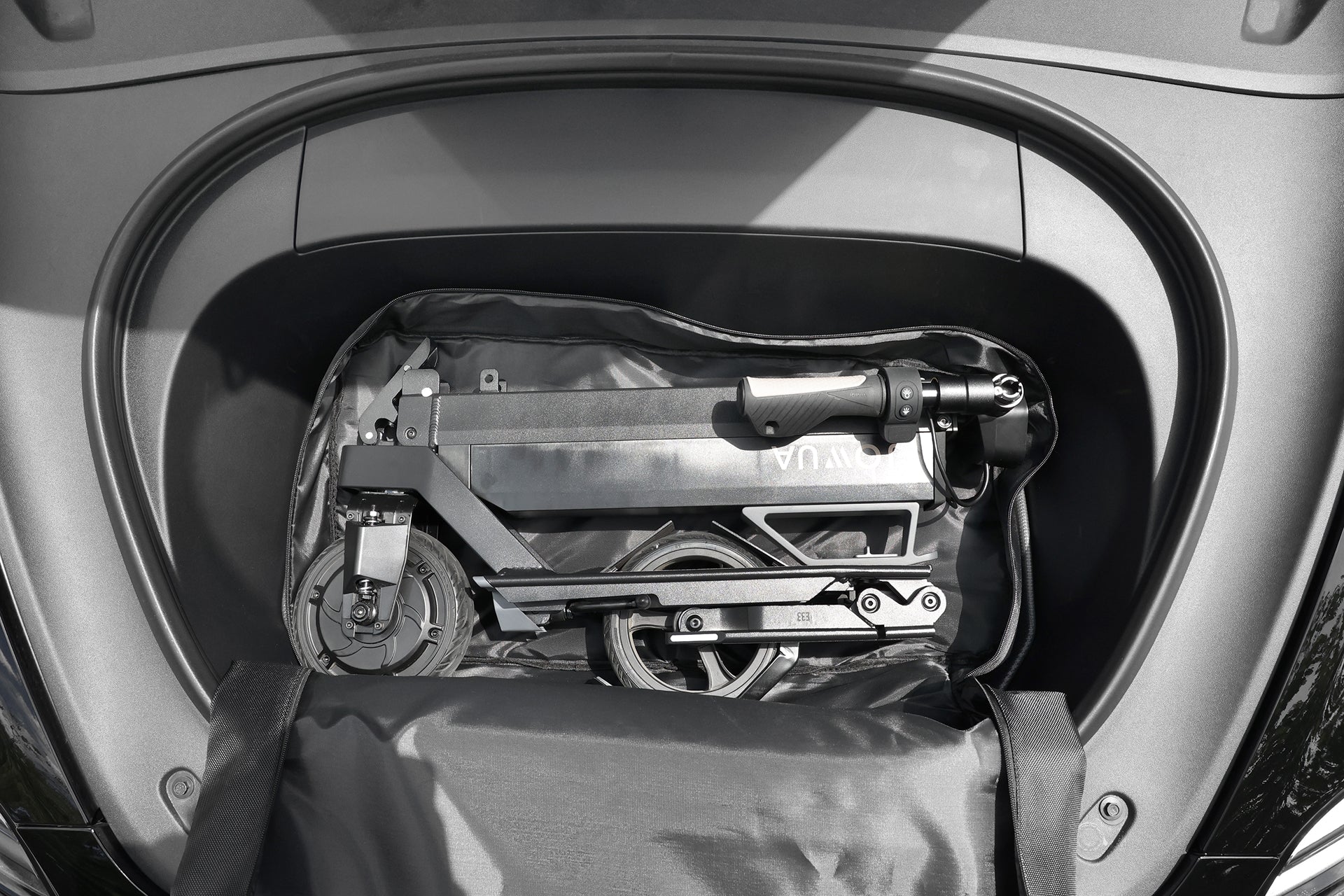 A JOWUA Folding Electric Scooter｜Performance, featuring a long-range battery, is neatly stored inside the front trunk of a car with a protective cover.