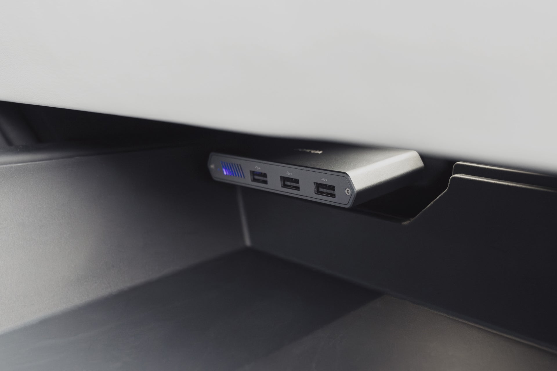 A close-up of the JOWUA Tesla 1TB SSD + 3-Port HUB, installed under a shelf with three USB ports and a blue LED indicator—perfect for Tesla Sentry Mode storage and connecting devices.