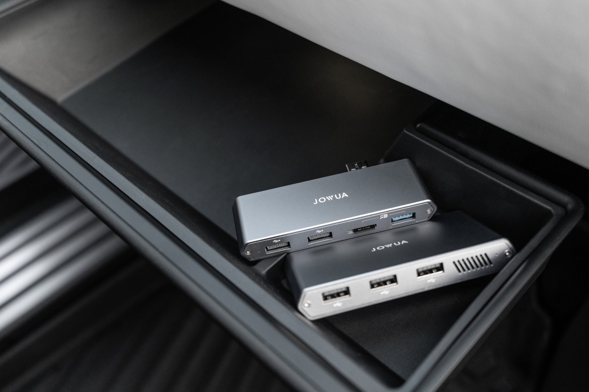 Two JOWUA Tesla 1TB SSD + 3-Port HUB devices are shown in the car's storage, displaying multiple USB ports and slots—perfect for device connectivity or boosting your Tesla Sentry Mode storage.