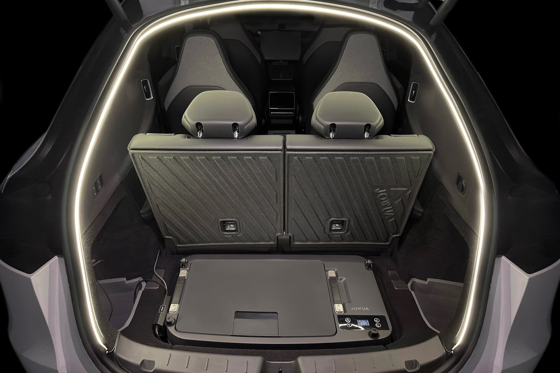 A slim, rectangular JOWUA Car Refrigerator for Tesla Model Y L (2026+) with intelligent dual-mode cooling sits on the floor of a vehicle’s cargo area behind the rear passenger seats.