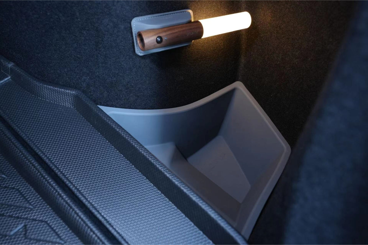 A close-up of JOWUA Trunk Storage Bins for Tesla Model 3 Highland (2024+) shows a gray compartment with a removable, tube-shaped LED light with wooden handle mounted on the side wall, perfect for organizing your trunk.