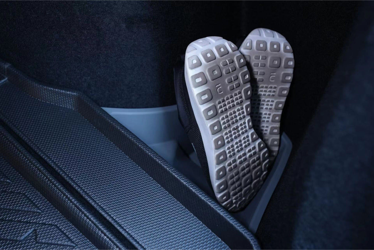 A pair of athletic shoes with textured soles is neatly stored upright in JOWUA Trunk Storage Bins for Tesla Model 3 Highland (2024+) inside a car trunk with a rubber floor mat.