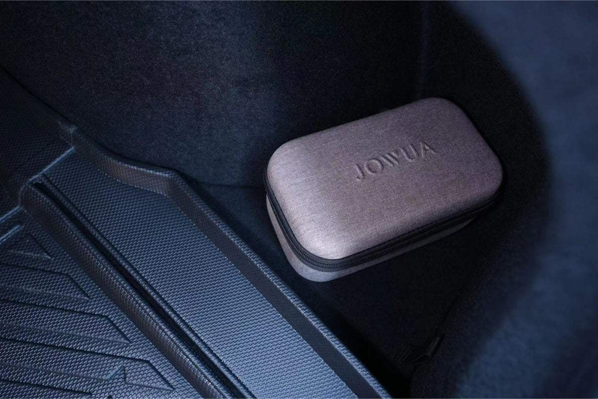 A small, rectangular gray JOWUA Trunk Storage Bin for Tesla Model 3 Highland (2024+) sits in the corner of a textured car trunk mat with black interior lining, perfectly complementing the trunk storage setup.