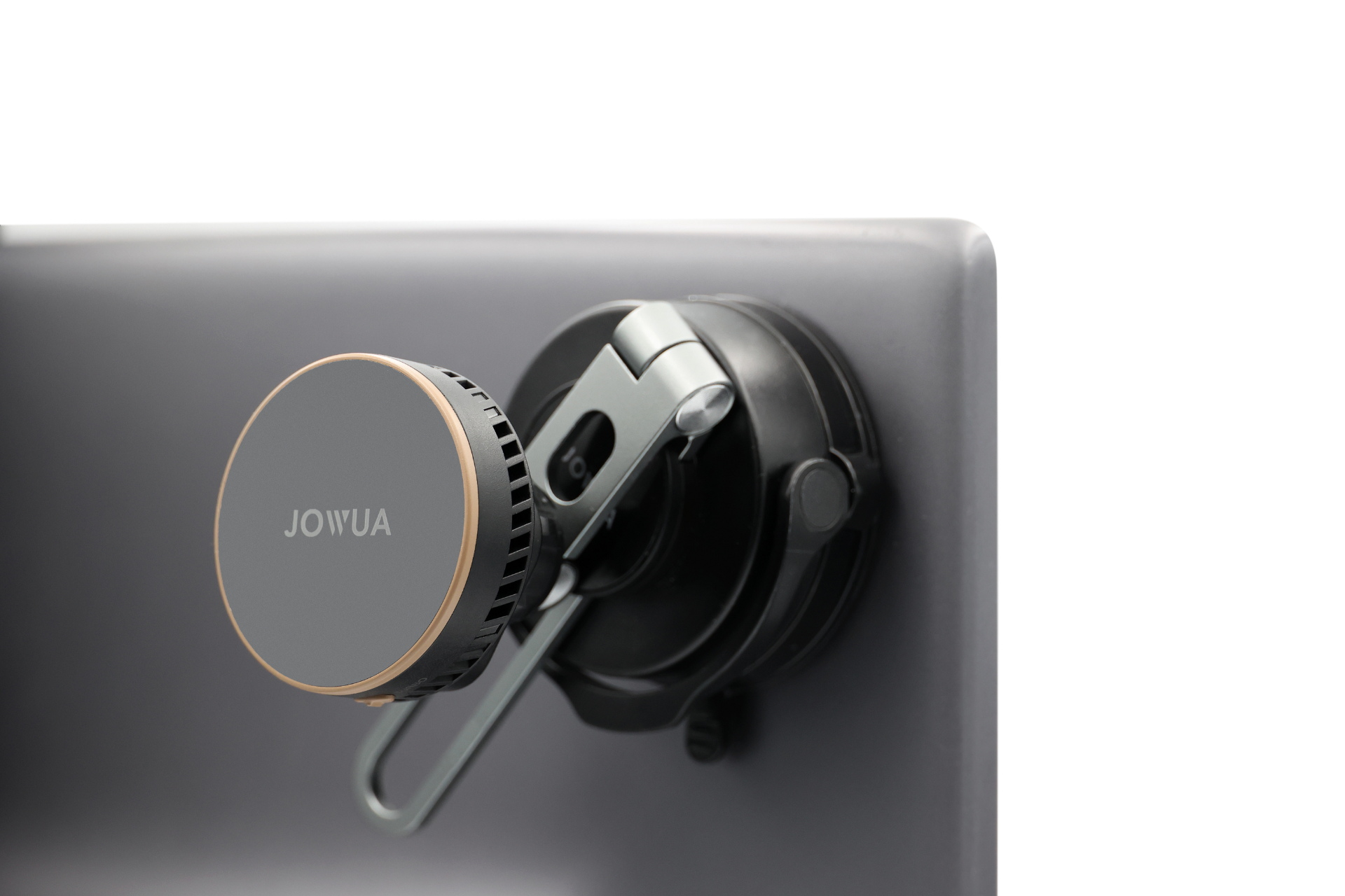 A close-up of a JOWUA Active Cooling 6D Tesla Compatible Invisible Foldaway Car Mount Qi2 Wireless Charger (MagSafe) clamped to the gray monitor edge, shown against a white background.