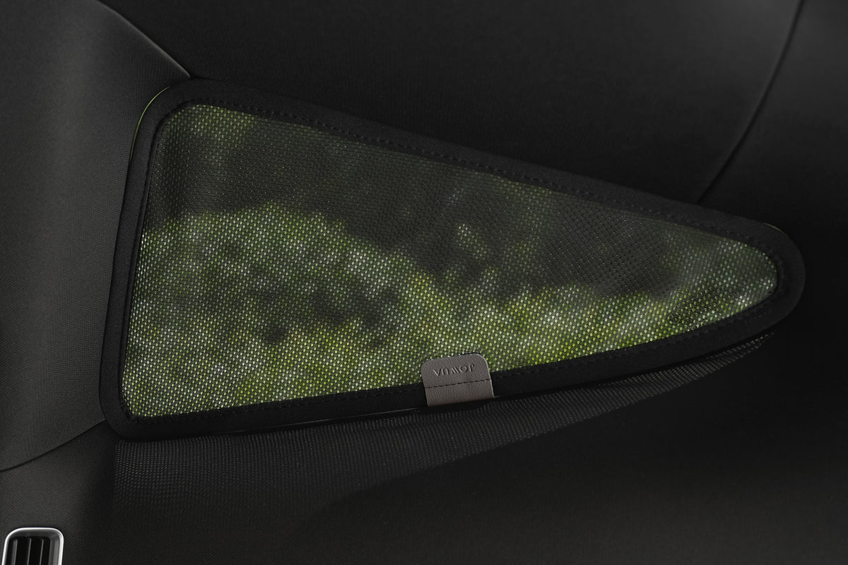 Close-up of the JOWUA Rear Lift Gate + Triangular Window Sunshade for Model Y L (2026+) installed, showing its mesh material with a blurred green outdoor view visible through it.