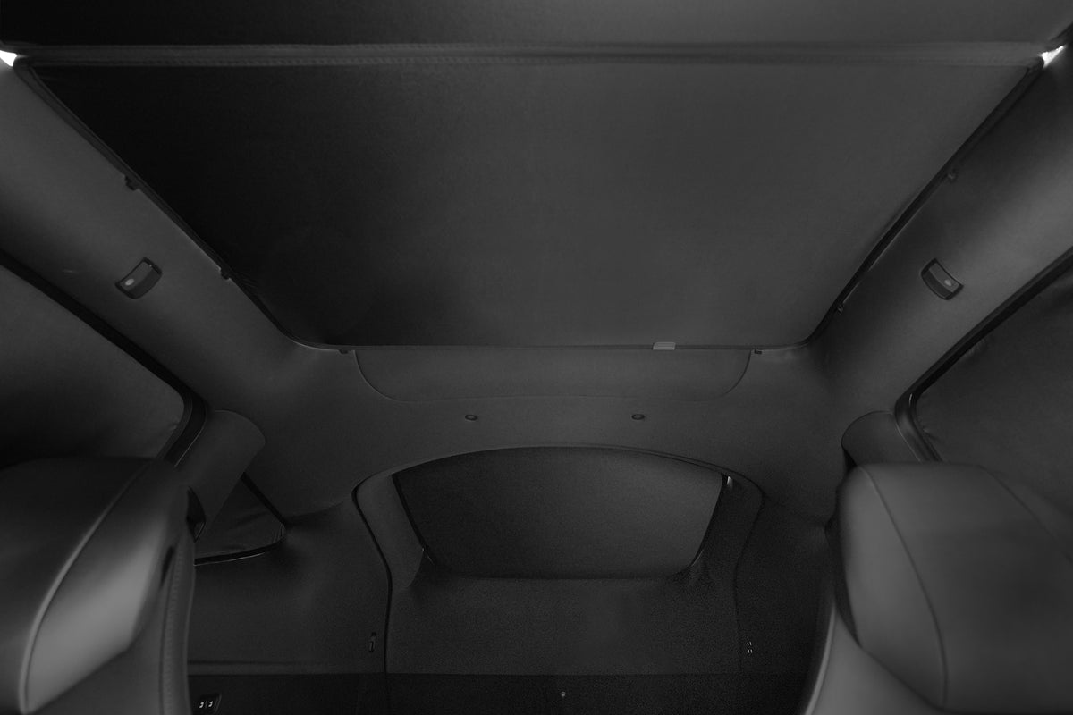 View from the back seat of a car looking up at a closed panoramic sunroof, featuring dark upholstery and minimal interior lighting, enhanced by the JOWUA Side + Rear Lift Gate Window Sunshade for Model Y L (2026+), which effectively blocks out excess sunlight for added comfort.
