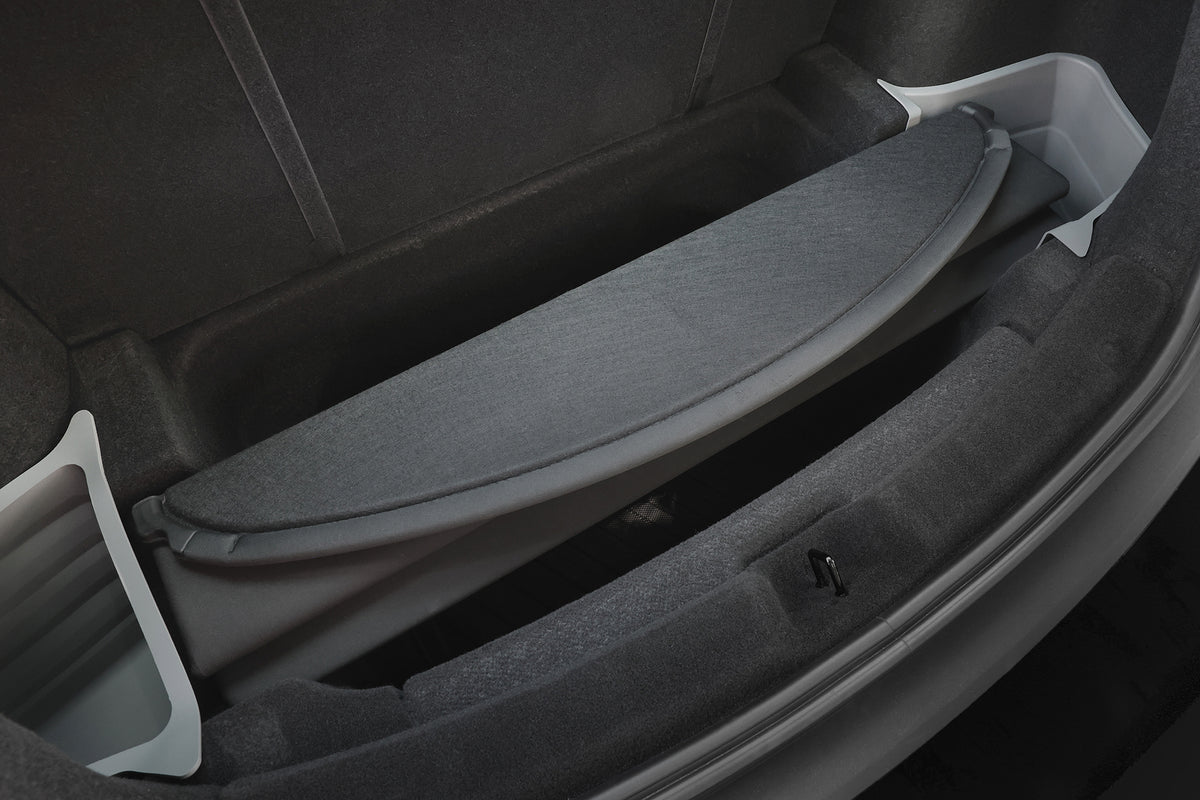 Close-up of a Model Y trunk with the JOWUA Model Y 2025+ Interior/Trunk Full Coverage Liner Combo. A removable gray cargo shelf reveals storage below, with dark fabric lining and light gray side accents for enhanced protection.