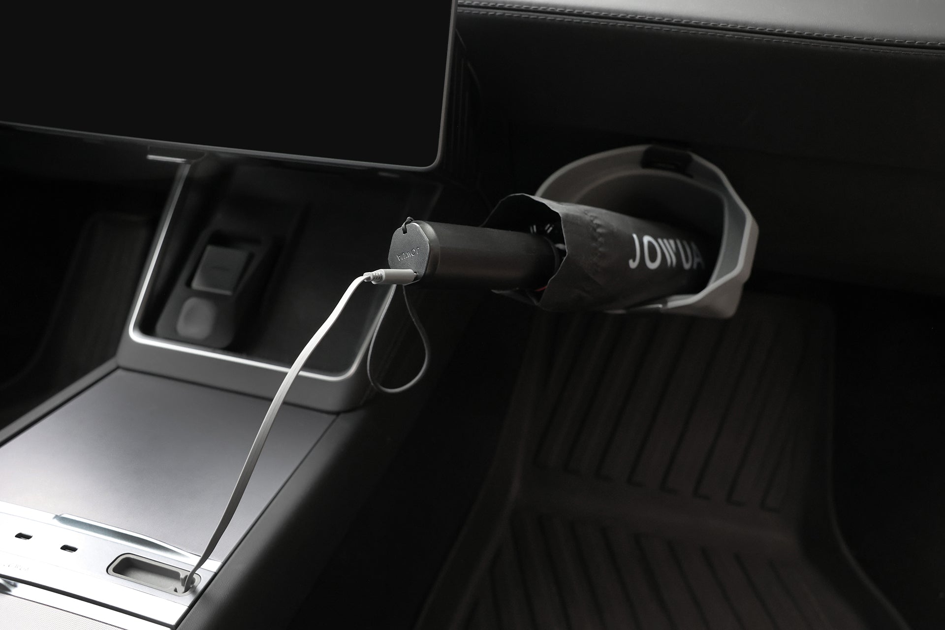 A JOWUA Type-C Electric Umbrella in black is kept in a dashboard holder, with its white USB Type-C charging cable connected to a nearby car port.