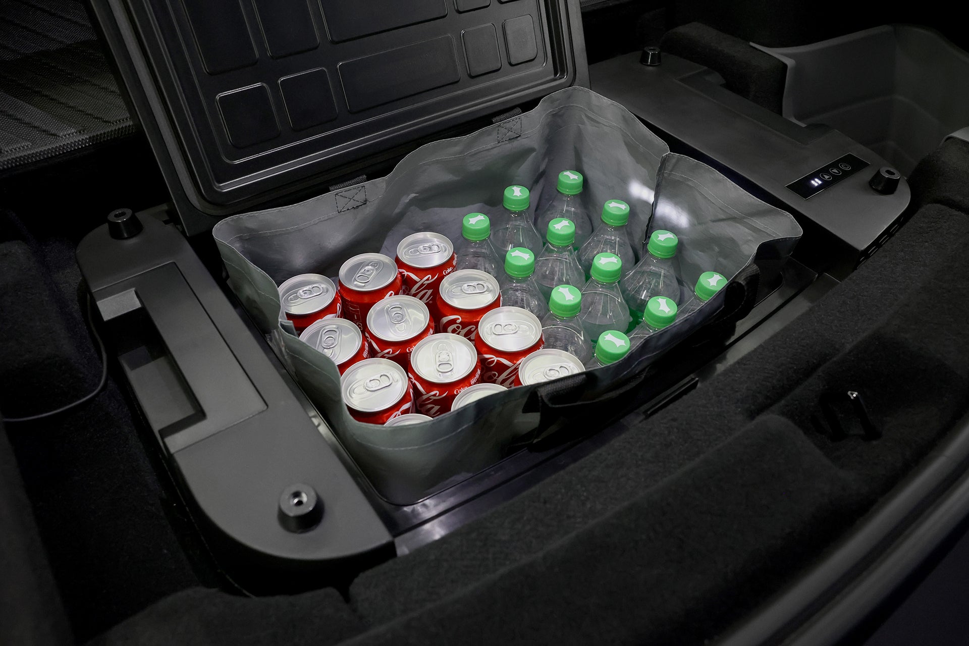 The JOWUA Car Refrigerator for Tesla Model Y, featuring intelligent dual-mode cooling, keeps cans of soda and green-capped plastic water bottles neatly organized inside a flexible liner in your trunk.