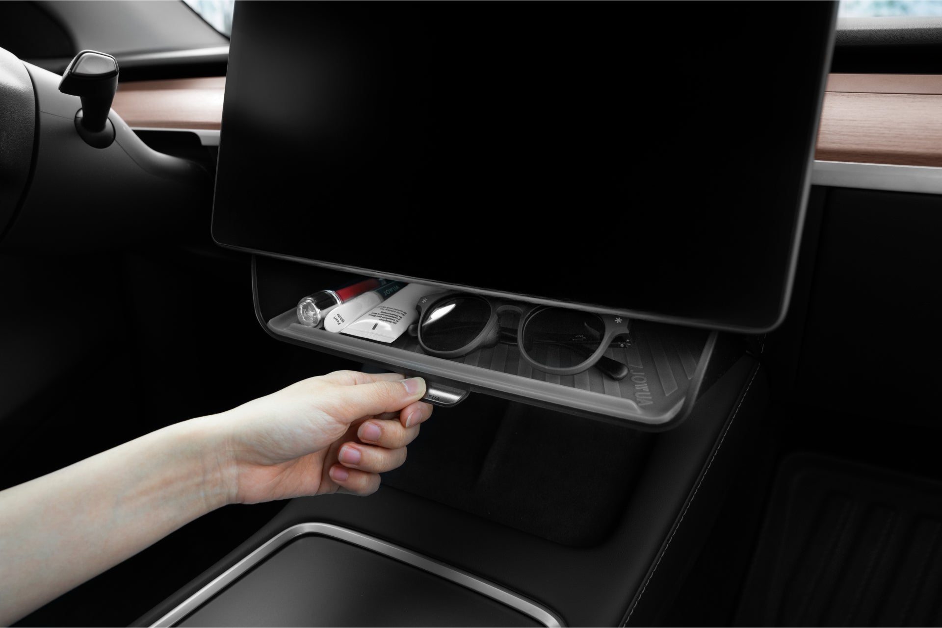 A person opens a storage compartment in a Tesla Model 3 Highland, revealing the JOWUA Tesla Charging Essentials Set—an Apple accessory kit neatly organizing MagSafe-compatible devices and essentials for seamless in-car integration.
