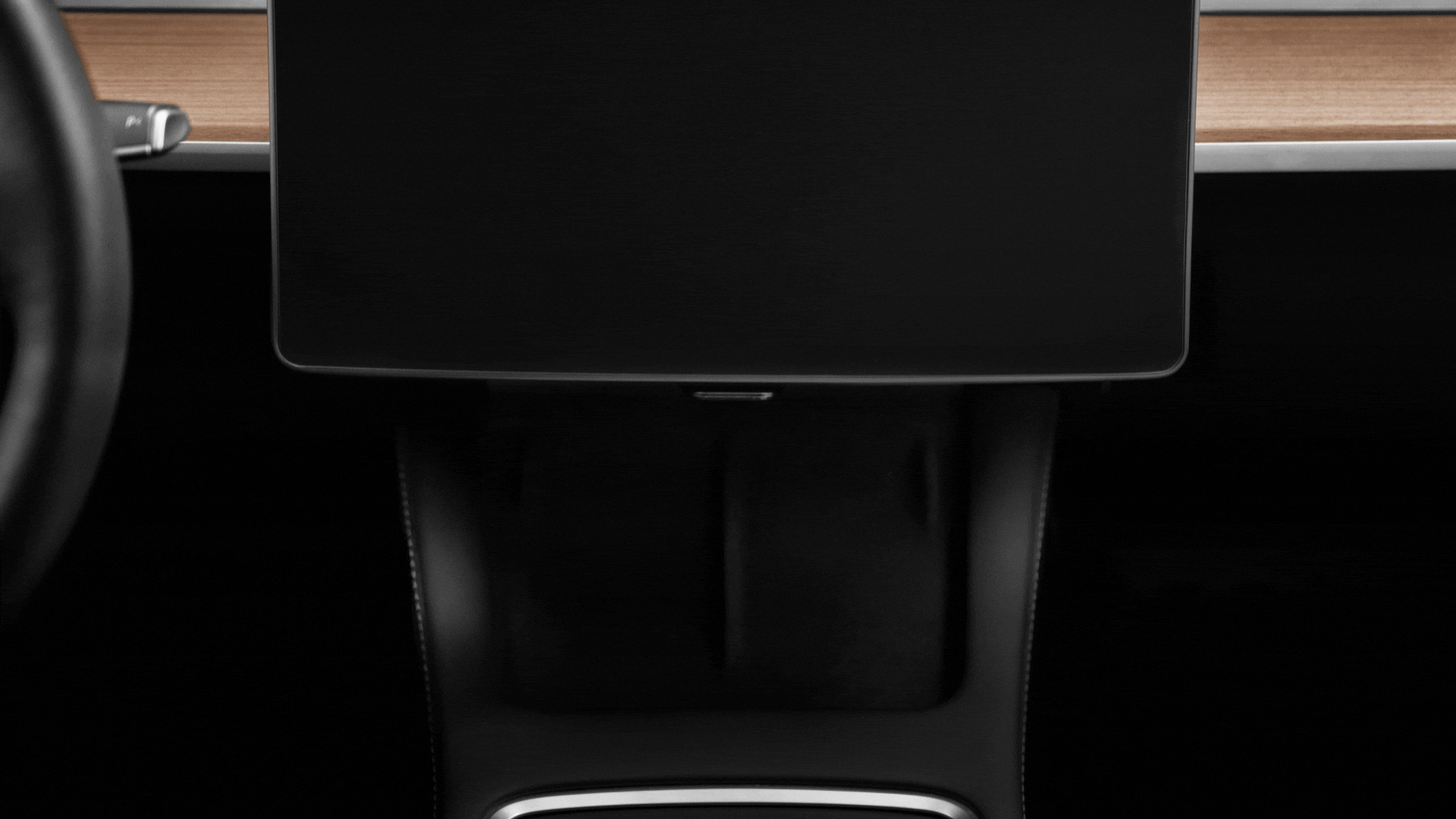 Close-up of a car interior featuring JOWUA’s Tesla Everyday Essentials—a large central touchscreen with Apple integration, set in a wooden dashboard and black center console with white stitching. The steering wheel edge is partially visible on the left.