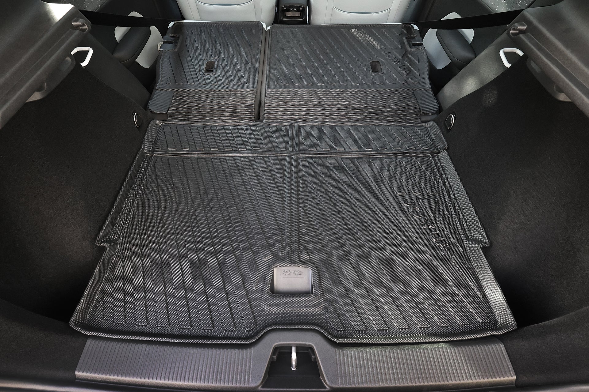 The image displays the rear cargo area of a Volvo EX30 with the back seats folded flat, protected by a black, textured All Weather Trunk Liner + Rear Seat Cover from JOWUA.