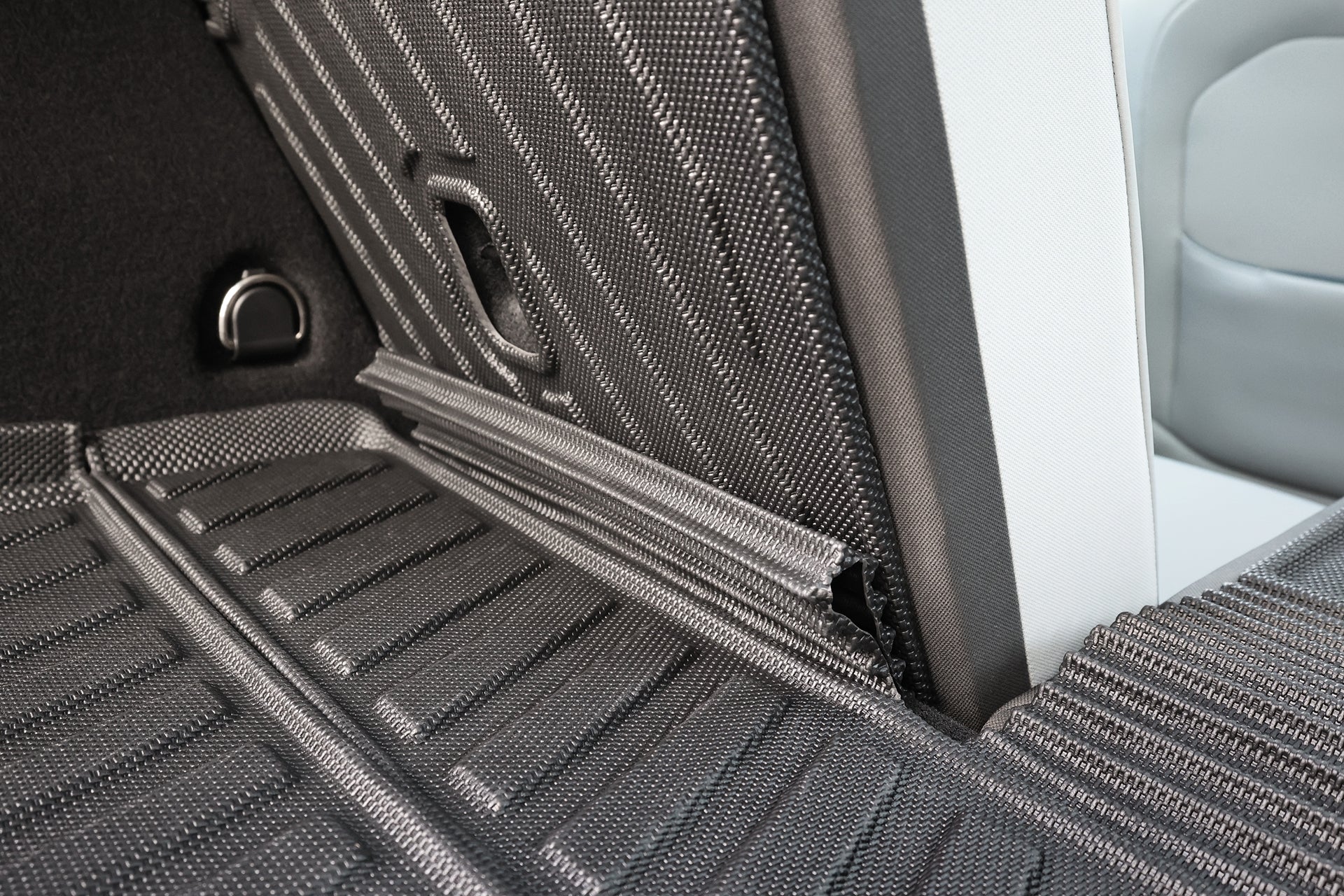 Close-up of JOWUA All Weather Trunk Liner + Rear Seat Cover (Volvo EX30) showing the textured fabric upholstery, joint between seatback and cargo area, and liner protecting the floor.