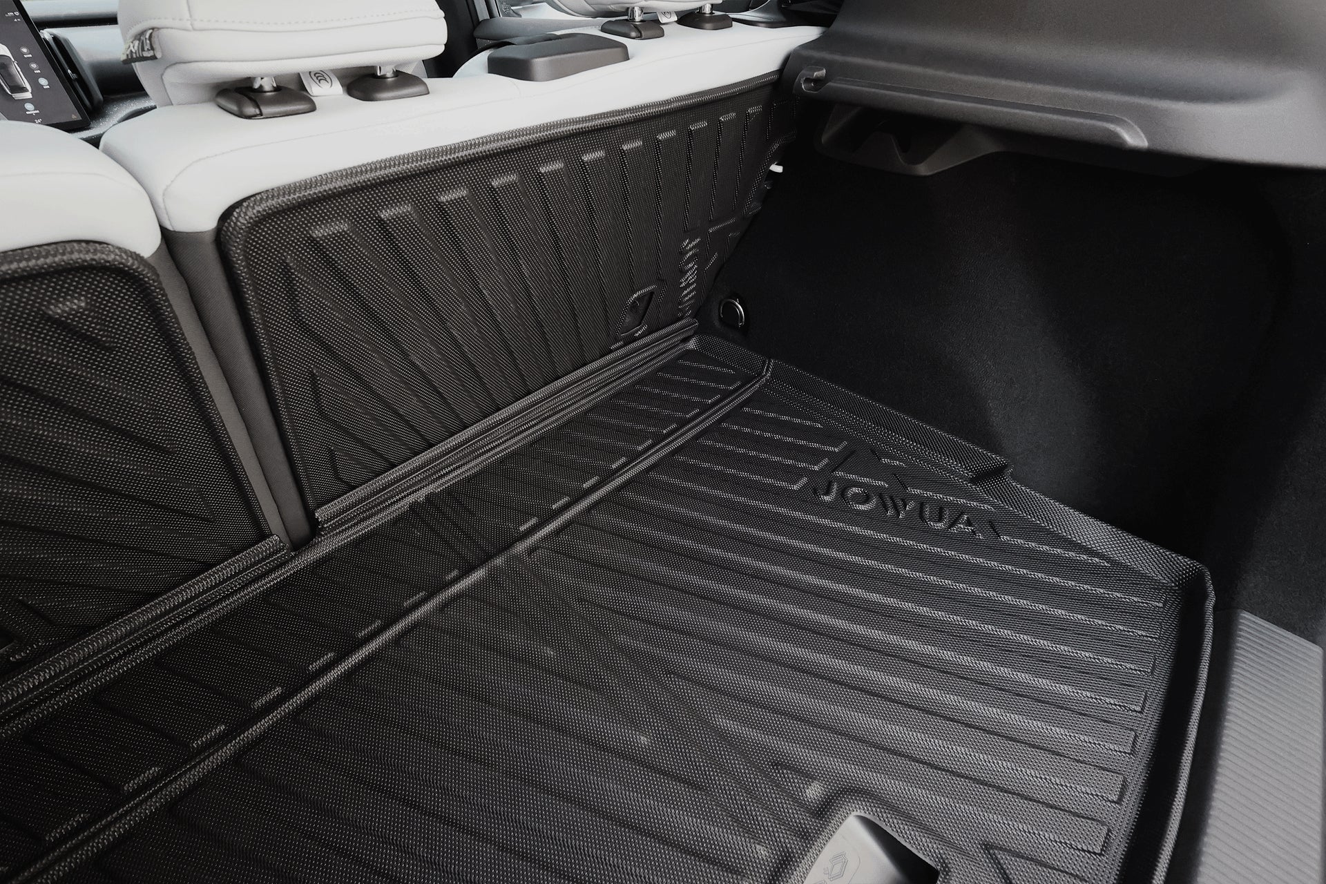 The JOWUA All Weather Trunk Liner + Rear Seat Cover for Volvo EX30 features a black textured, custom-fit mat with raised edges, shown here with light-colored folded rear seats and visible side panels in the background.