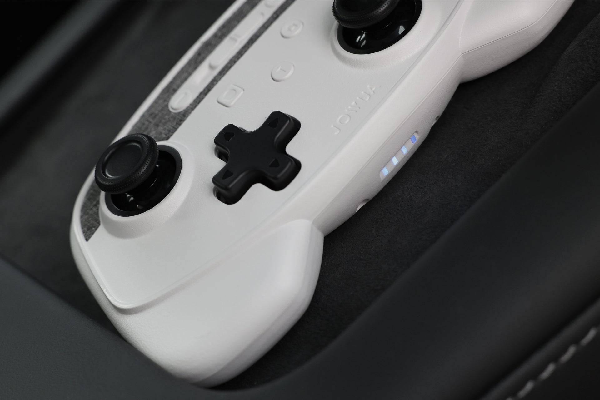 Close-up of a white JOWUA Wireless Tesla Game Controller with black joysticks and buttons, resting on a dark surface. Three indicator lights are illuminated. Compatible with Tesla Model 3 (2018-2023) and Model Y (2018-2024).