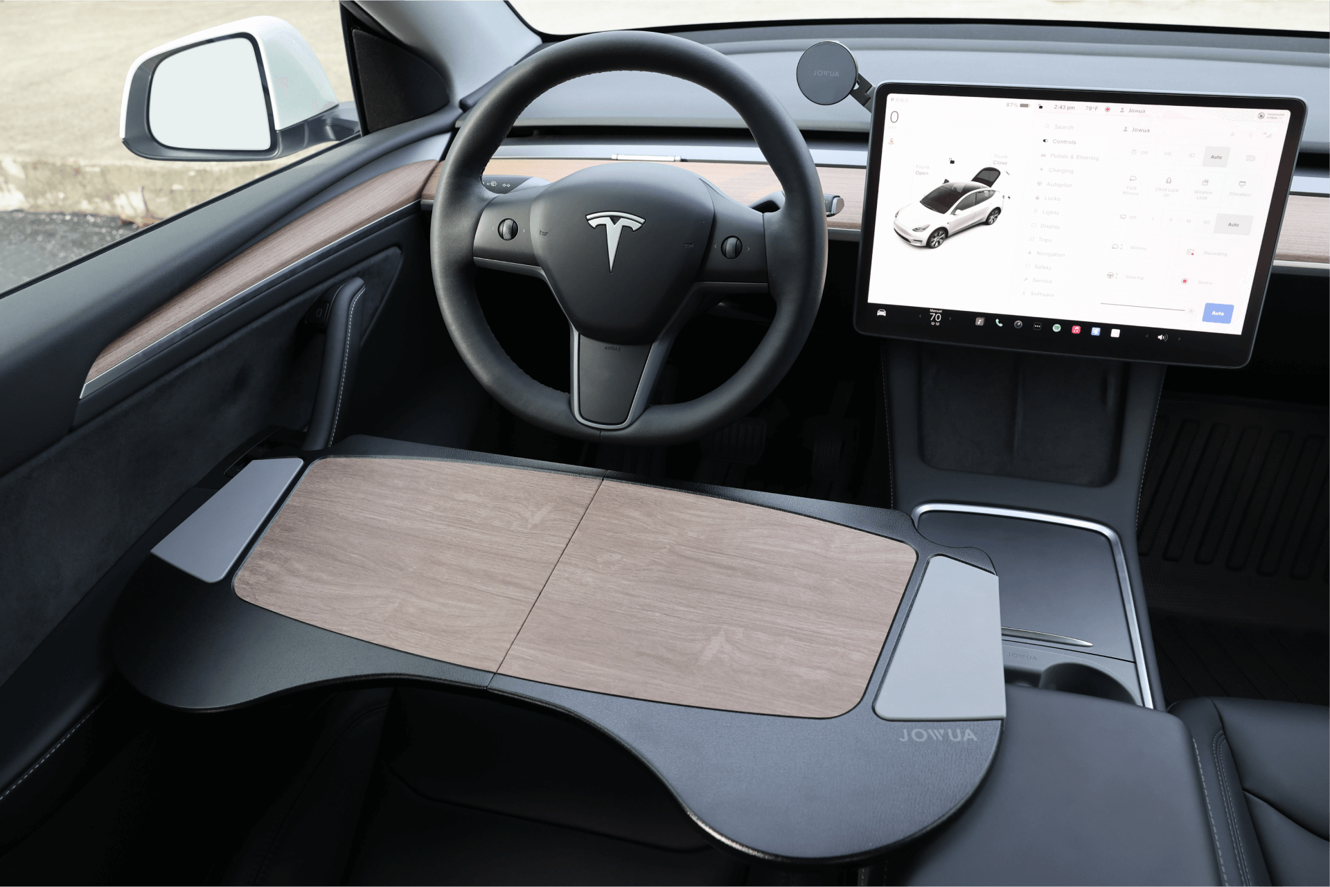 Interior view of a car showcasing a sleek steering wheel with the Tesla logo, a large digital display presenting vehicle information, and the JOWUA Foldable Car Tray Bundle elegantly positioned over the center console.