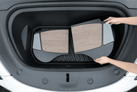 A person places two JOWUA Model 3 All Weather Trunk Combo mats, specifically designed for the reengineered Model 3 Highland (2024+), inside the trunk of their Tesla. These mats are crafted from waterproof TPE material and feature a distinctive wood-like pattern with black borders, perfectly complementing the stylish interior of their vehicle.