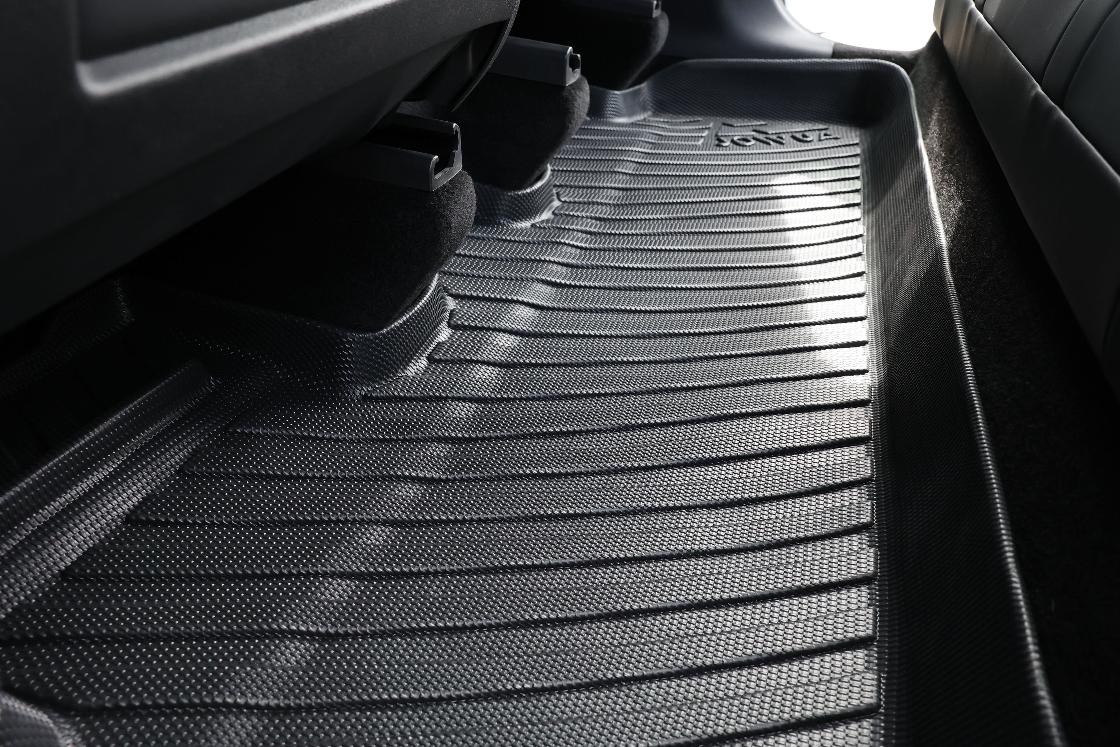 Close-up of a JOWUA Premium Interior Essentials Set (RHD) – Model Y Juniper all-weather black floor mat, textured for grip, covering the rear area and extending under seats to protect the premium interior from dirt and moisture.