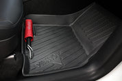 A red umbrella rests on a textured black JOWUA Premium Interior Essentials Set – Model Y Juniper floor mat, showcasing stylish accessories in the front passenger footwell.