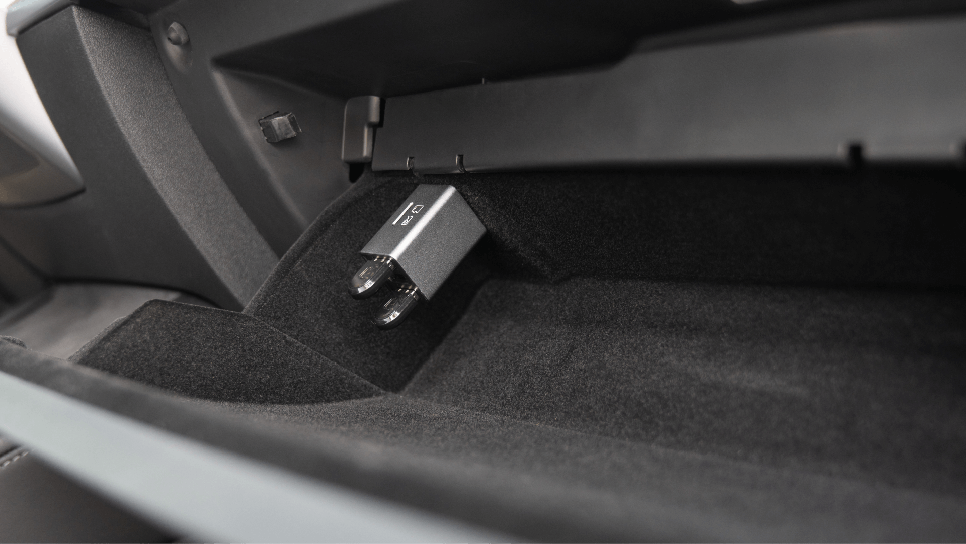 The image features a car glove compartment with a JOWUA 3 Port USB HUB with DashCam Reader inserted into the port. The interior is lined with black fabric and plastic, adding a sleek touch to this Tesla USB hub setup.
