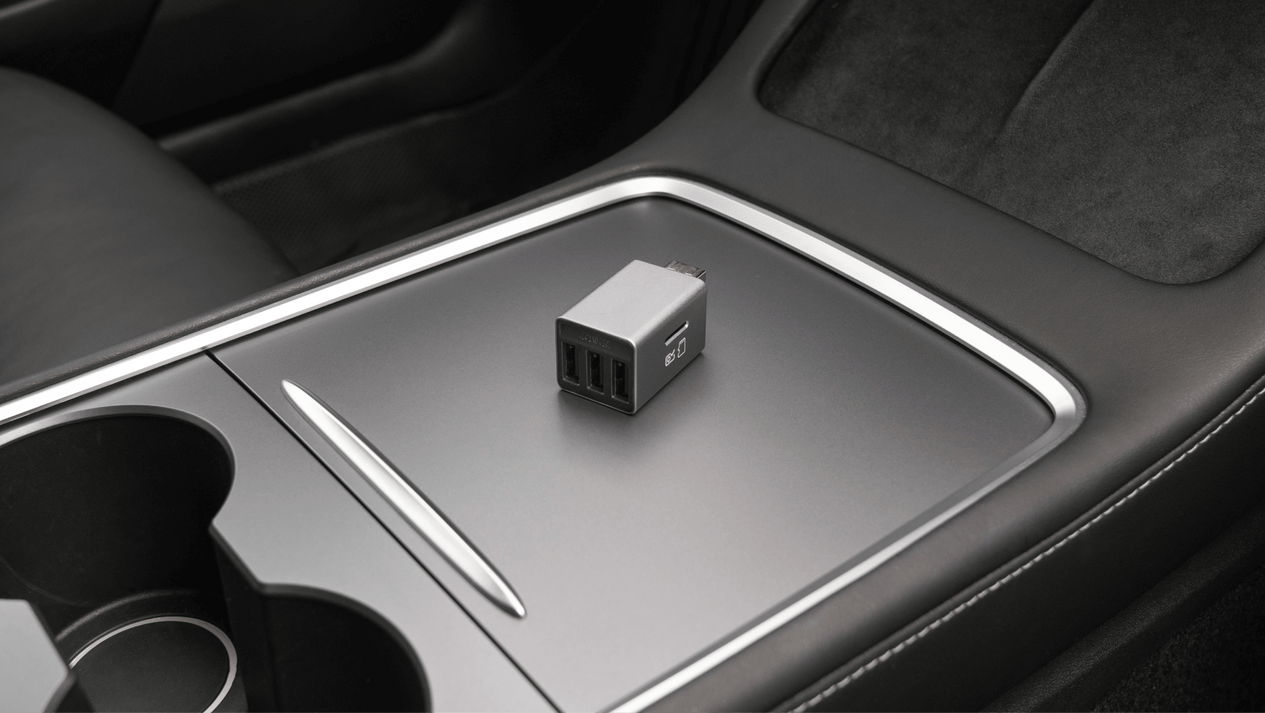 A USB car charger with two ports sits on the stylish JOWUA 3 Port USB HUB with DashCam Reader within the vehicle