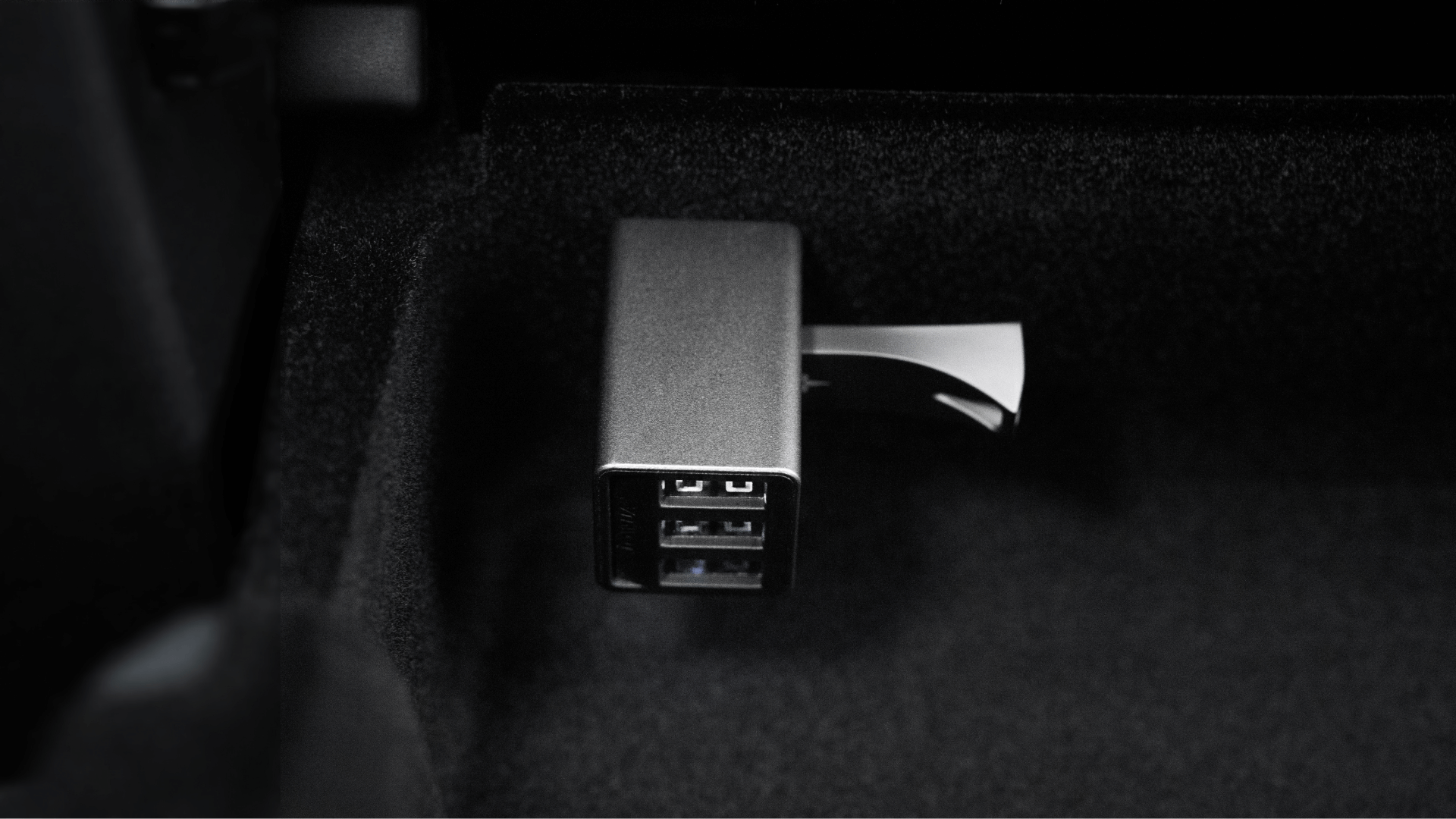A close-up of the JOWUA 36W Hub Charging Combo on a dark surface, resembling a sleek Tesla USB Hub, with a USB drive inserted. The metallic rectangular charger displays multiple slots.