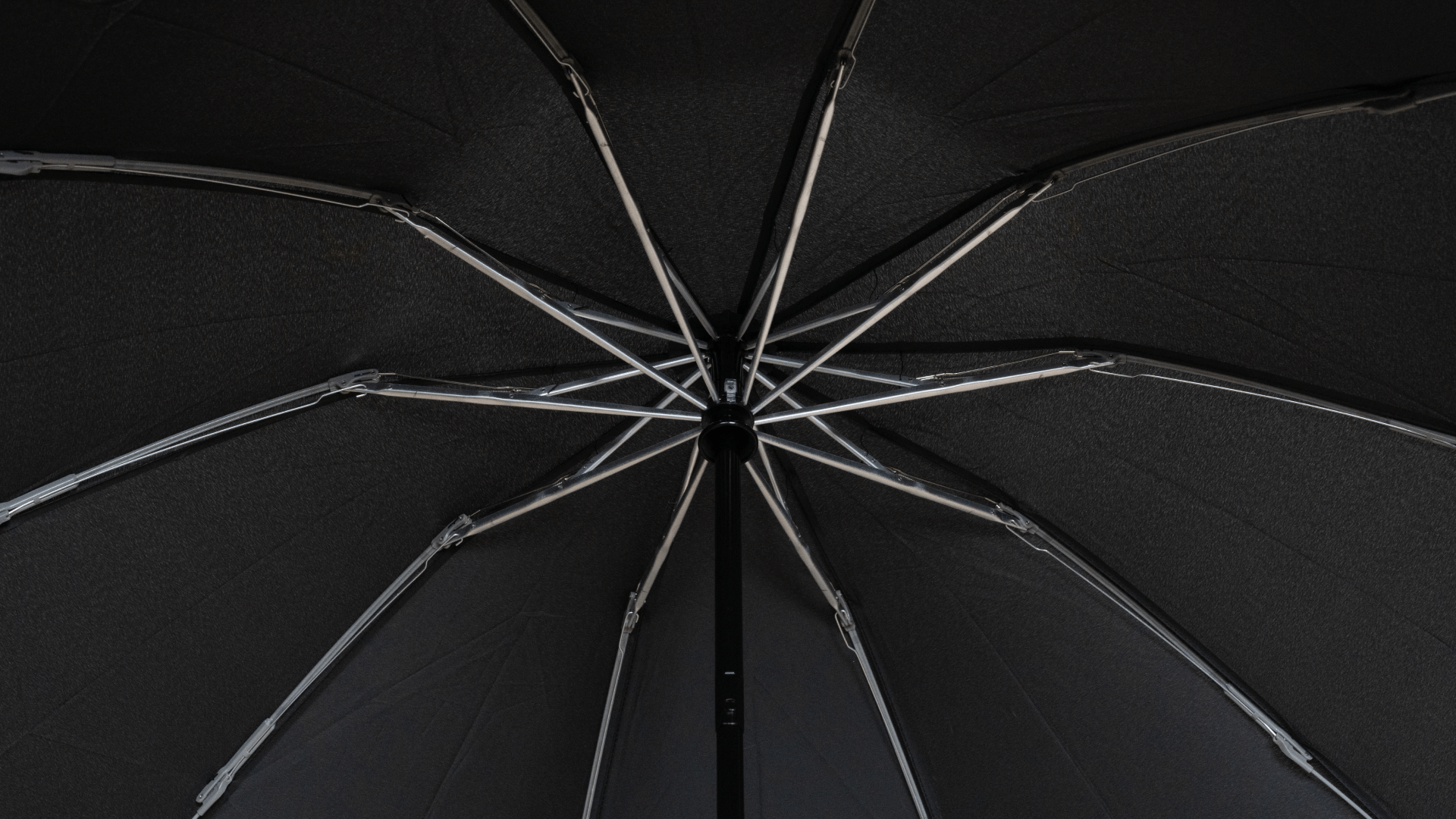 Close-up view of the interior of an open Tesla Color Matching Umbrella (Anti-rebound Inverted) by JOWUA, highlighting the intricate silver spokes and central shaft. The water-repellent fabric creates a geometric pattern against the dark background, ensuring you stay dry and stylish on rainy days.