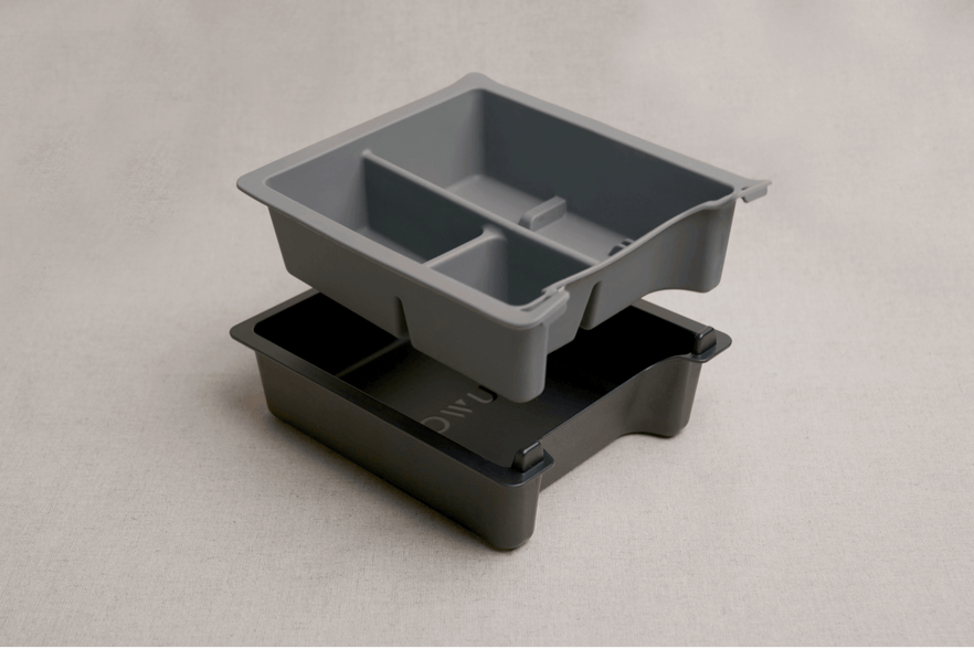 Displayed as a sophisticated center console solution, the Center Console Tray Organizer by JOWUA is perfect for Tesla Model 3/Y accessories. This set includes two nested trays: a top tray in gray with three sections over a darker bottom tray. Both trays are elegantly placed on a light beige surface and crafted from premium hybrid material to ensure lasting durability and style.
