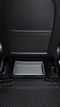 The image displays the back seat area of a car equipped with the JOWUA Under Seat Collapsible Organizer for Tesla Model X Y, placed on the floor behind the front seat. The interior also features black upholstery and textured rubber floor mats, highlighting its versatile utility.