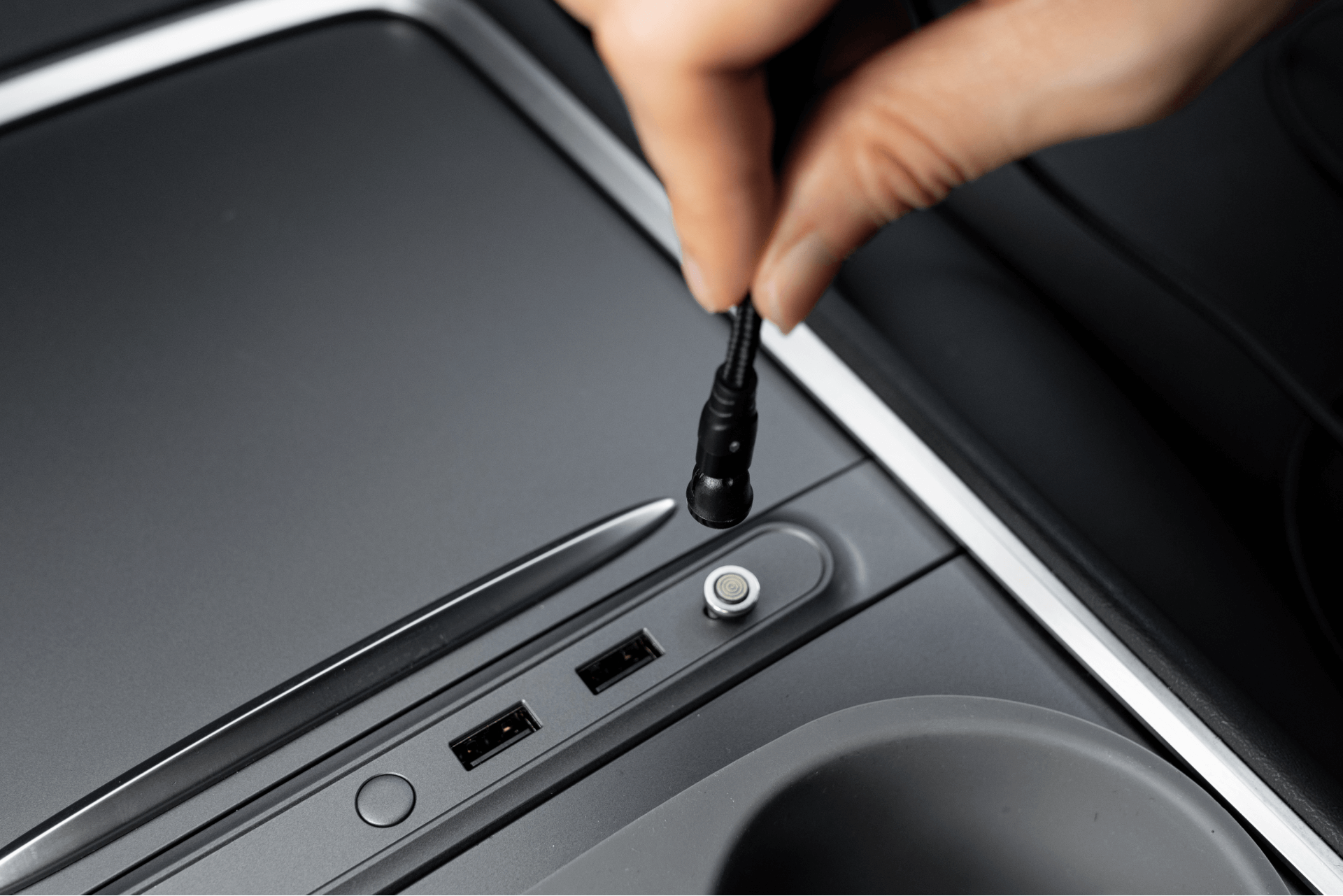 A hand connects the JOWUA Magnetic Charging Cable USB-C to USB-C (1M-1.8M) into the car's center console, adjacent to USB ports and concealed slots, highlighting connectivity and electronic features. Ideal for Tesla Model 3 accessories fans looking for efficient solutions.