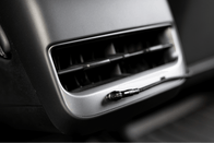 Close-up of a Tesla Model 3 interior highlighting an air vent alongside a JOWUA Magnetic Charging Cable USB-C to USB-C connected to an auxiliary input. The vent slats are open, enclosed by dark paneling with a sleek metallic finish.