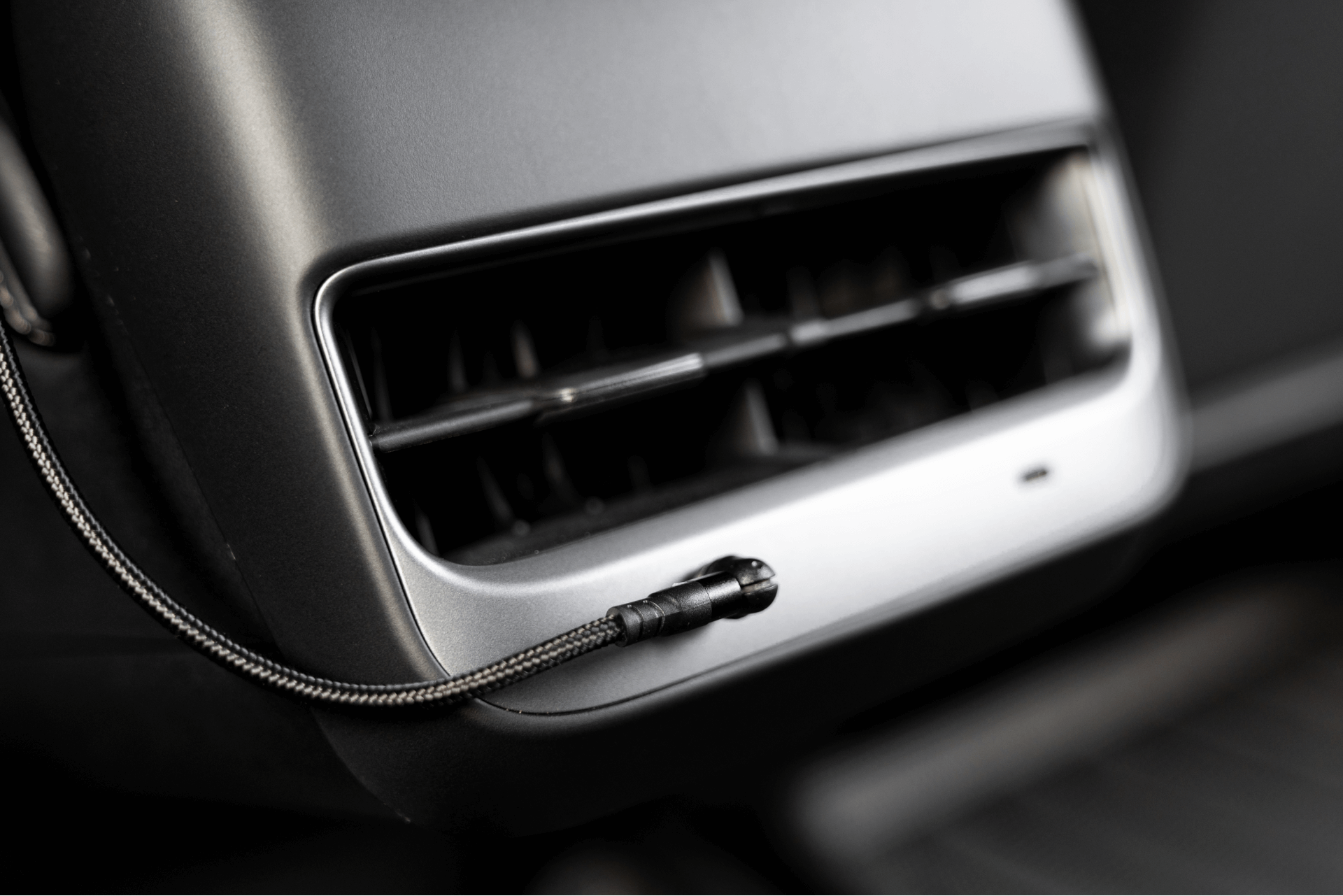 In a close-up view of the Tesla Model 3 interior, you can see an air vent with a sleek, modern design. A JOWUA Magnetic Charging Cable USB-C to USB-C (1M-1.8M), with its braided black design, is connected at the bottom right of the vent, ensuring quick and efficient power delivery for convenience on the go.