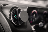 A car interior displaying a JOWUA Universal MagSafe Car Mount for Air Vents, highlighting its MagSafe compatibility. In the background, the dashboard and part of the infotainment system with lit-up dials are visible.