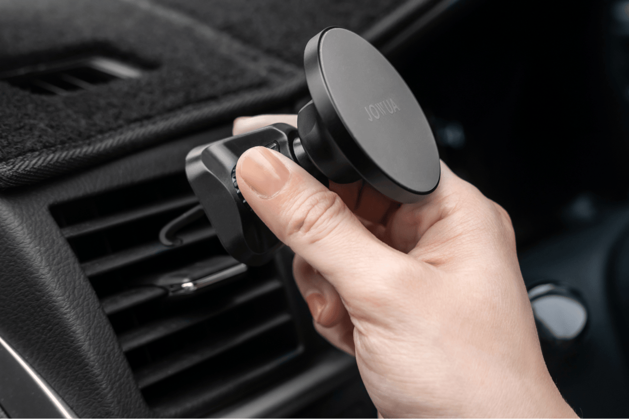A person adjusts a JOWUA Universal MagSafe Car Mount for Air Vents, which features 360° rotation. The mount is round and black, keeping your device perfectly positioned for every journey.